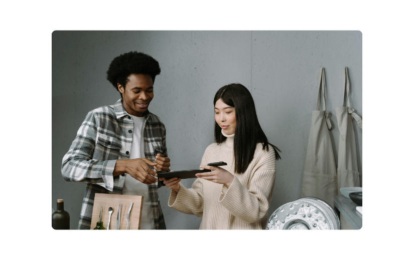 Two people reviewing product options on a tablet, highlighting the need for the best eCommerce platform for online sales.